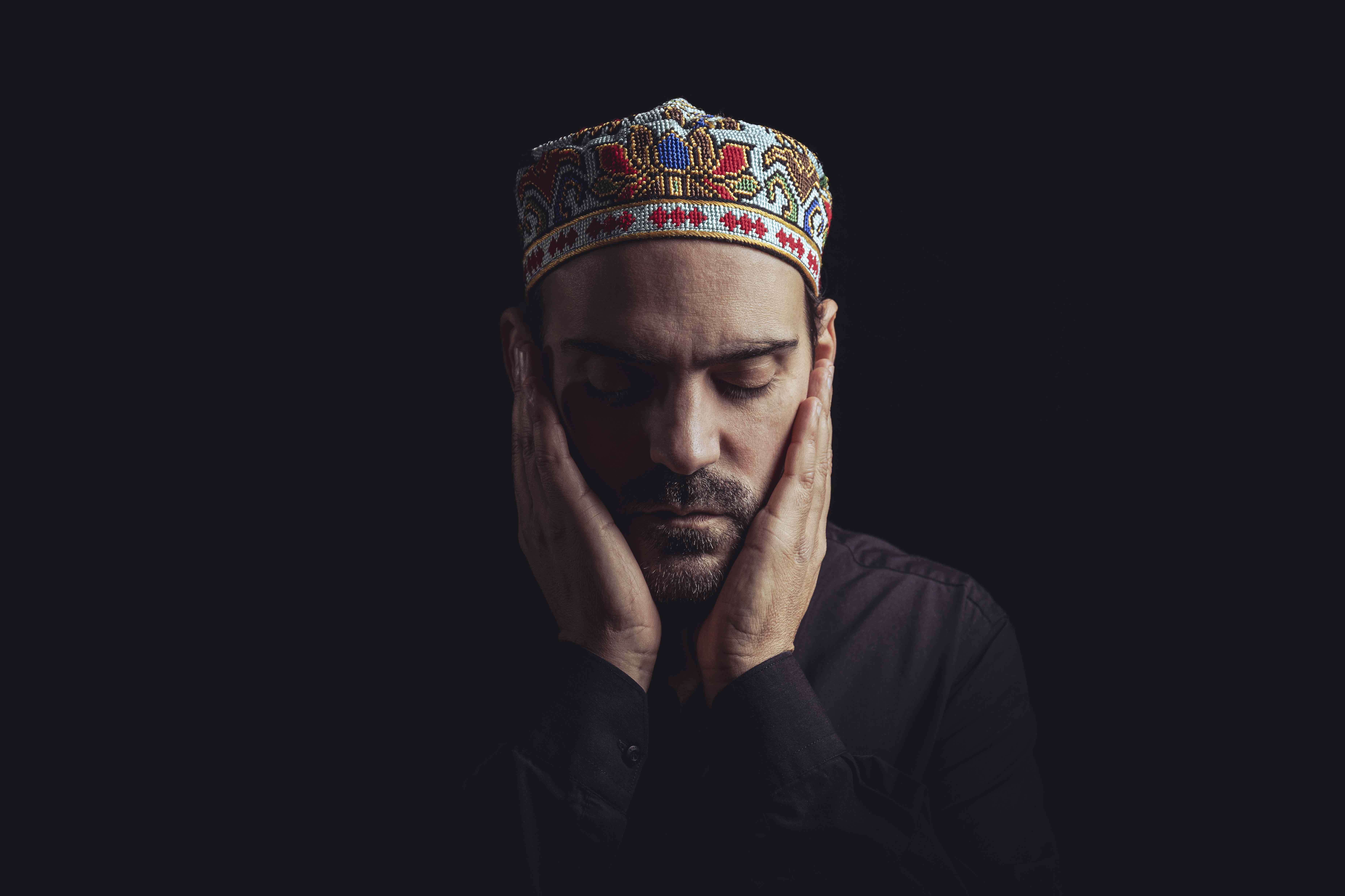 Blaise Ubaldini in contemplative pose, wearing a colorful Sufi-inspired hat, evoking serenity and introspection.